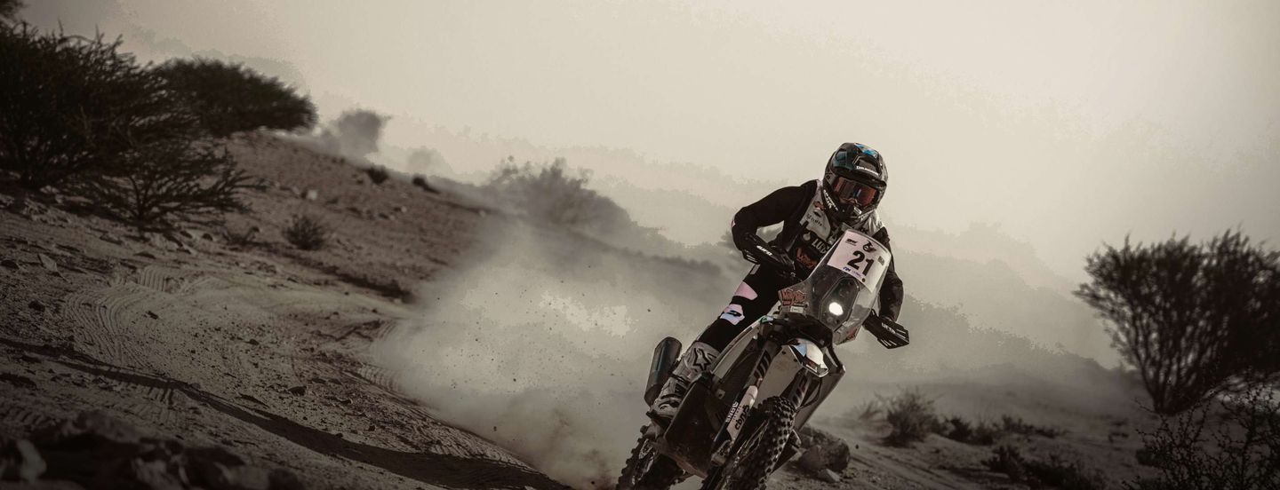 Alex McInnes riding his number 21 rally bike through desert dust